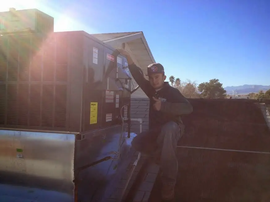 HVAC technician performing Air Duct Cleaning on a rooftop unit in Woodfield